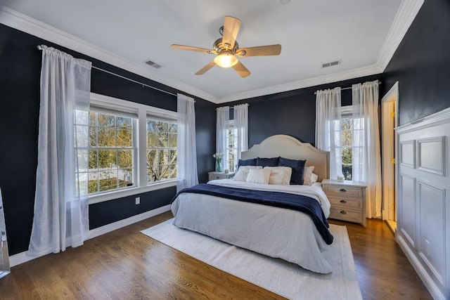 bedroom featuring crown molding, dark wood finished floors, visible vents, ceiling fan, and baseboards