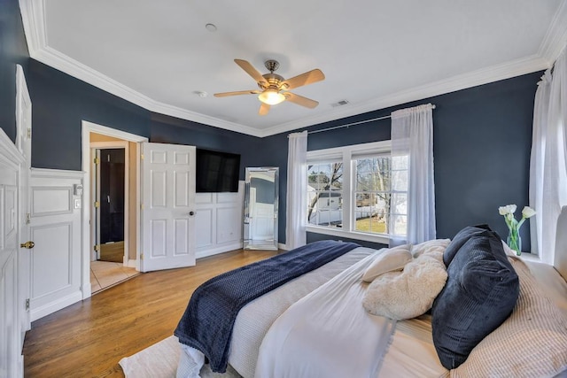 bedroom featuring ornamental molding, a ceiling fan, visible vents, and wood finished floors