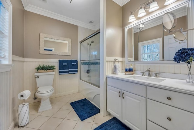 bathroom featuring tile patterned flooring, toilet, shower / bath combination with glass door, wainscoting, and crown molding