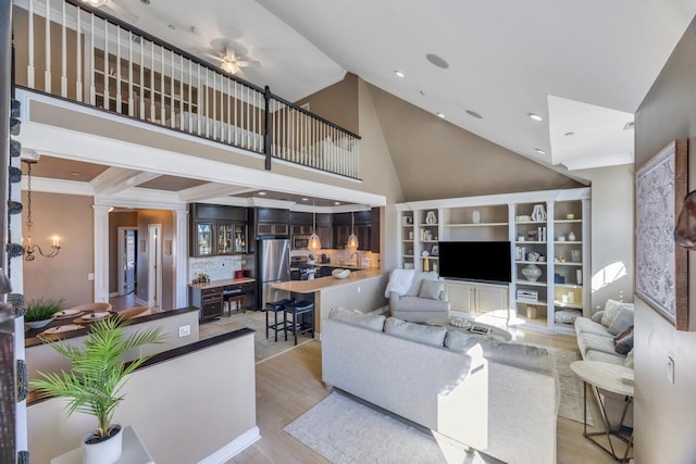 living area with crown molding, recessed lighting, a high ceiling, light wood-type flooring, and ornate columns