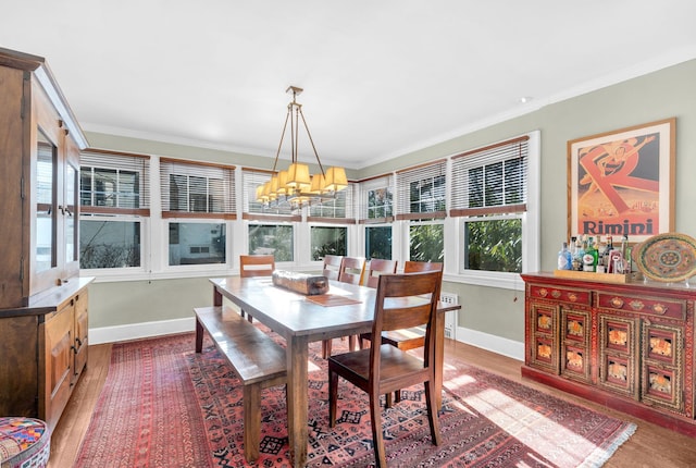 dining room featuring ornamental molding, a chandelier, baseboards, and wood finished floors