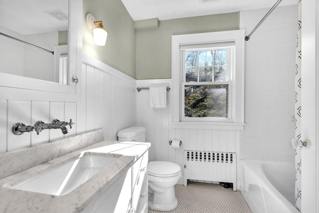 bathroom with toilet, a wainscoted wall, visible vents, radiator, and shower / bath combo