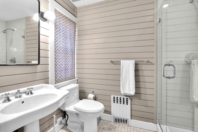 full bathroom with radiator, a stall shower, wooden walls, and toilet