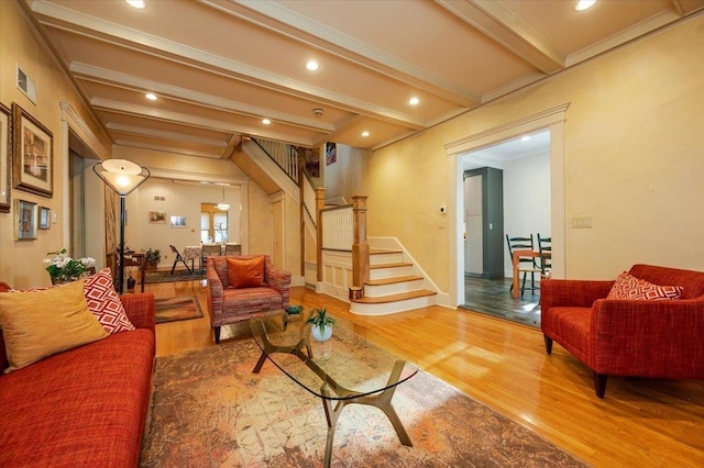 living room with crown molding, stairway, beam ceiling, and wood finished floors
