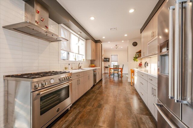 kitchen with light countertops, wall chimney range hood, backsplash, and high quality appliances