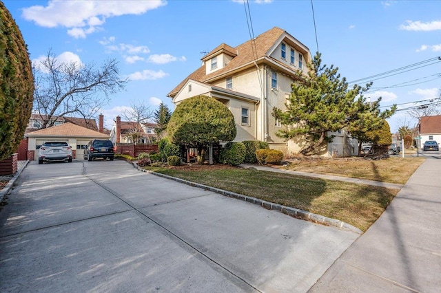 view of front facade with a detached garage, fence, and stucco siding