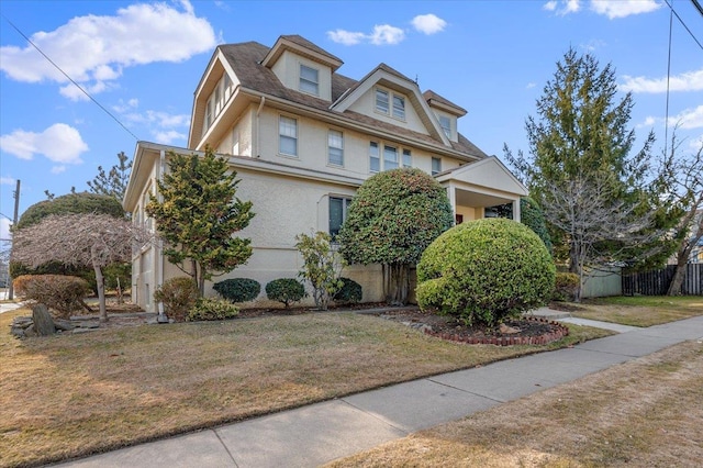 view of front facade with stucco siding, fence, and a front yard