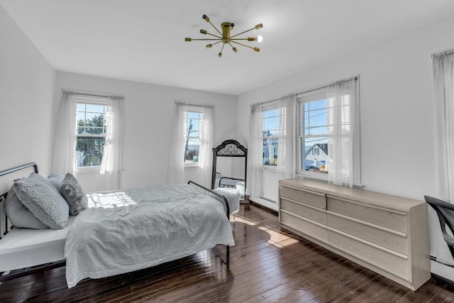 bedroom with a chandelier and dark wood finished floors