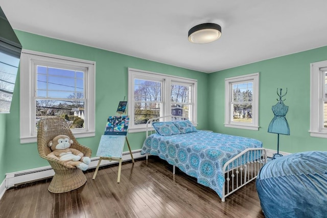 bedroom with a baseboard heating unit, hardwood / wood-style floors, and baseboards