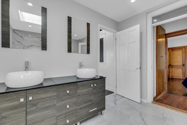 full bath featuring double vanity, marble finish floor, a sink, and recessed lighting