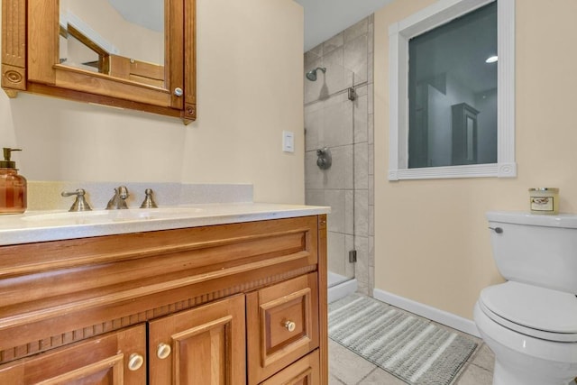 bathroom featuring toilet, a shower stall, vanity, baseboards, and tile patterned floors