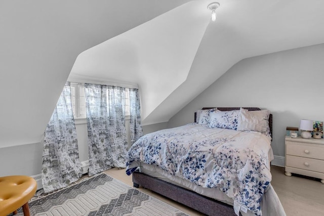 bedroom with vaulted ceiling and wood finished floors