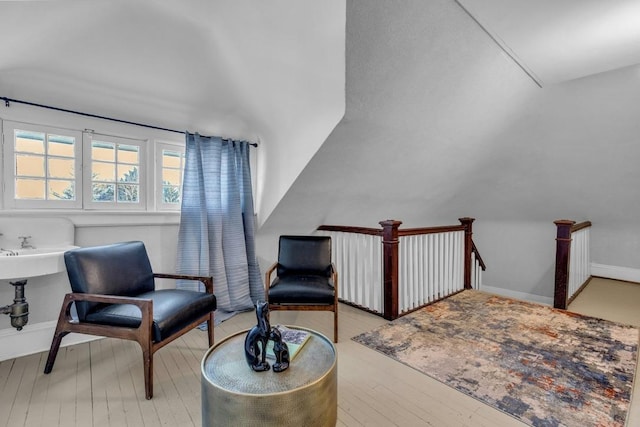 living area with baseboards, hardwood / wood-style floors, and an upstairs landing