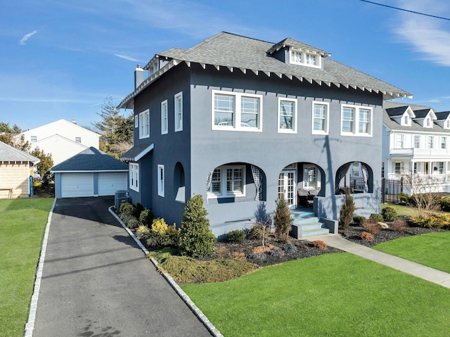 view of front facade featuring roof with shingles, central air condition unit, a garage, an outdoor structure, and a front lawn