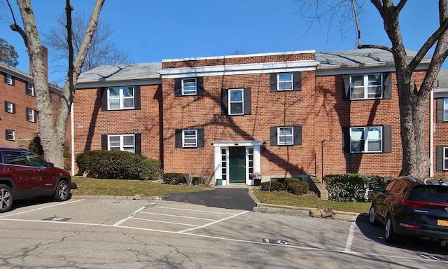 view of front facade featuring uncovered parking and brick siding