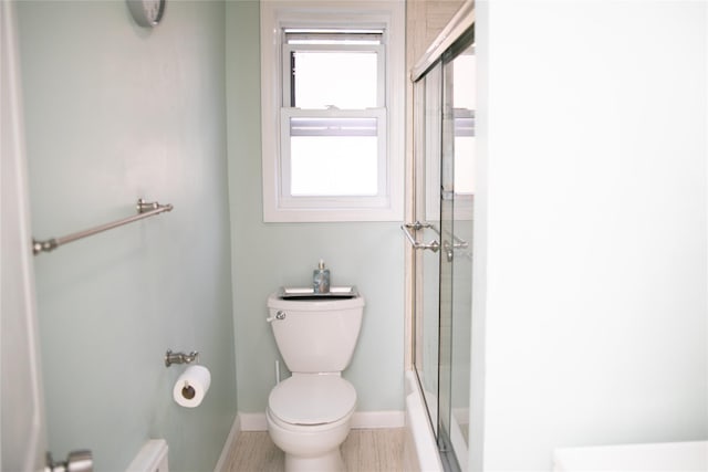 bathroom with shower / bath combination with glass door, toilet, and baseboards