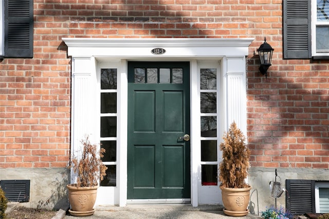 doorway to property with brick siding and visible vents