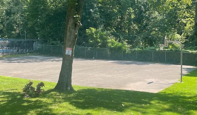 view of sport court with community basketball court, a lawn, and fence