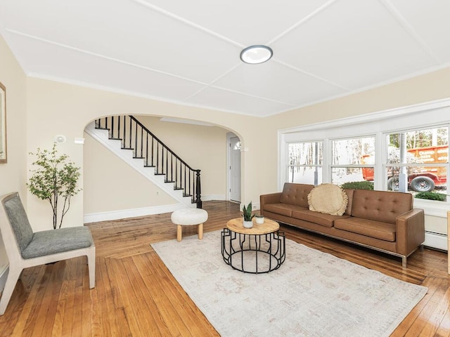 living room with stairway, arched walkways, a wealth of natural light, and wood finished floors