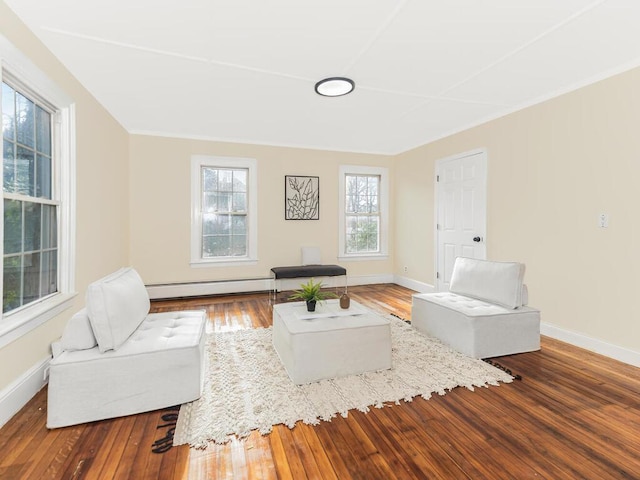 living area with baseboard heating, wood finished floors, and baseboards