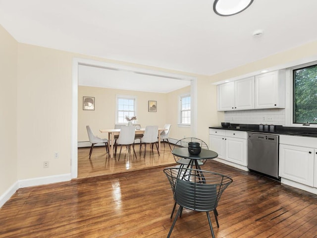 kitchen featuring tasteful backsplash, dark wood finished floors, dishwasher, dark countertops, and white cabinetry