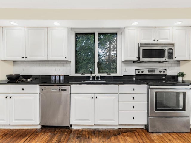 kitchen with stainless steel appliances, dark wood-style flooring, a sink, and white cabinetry