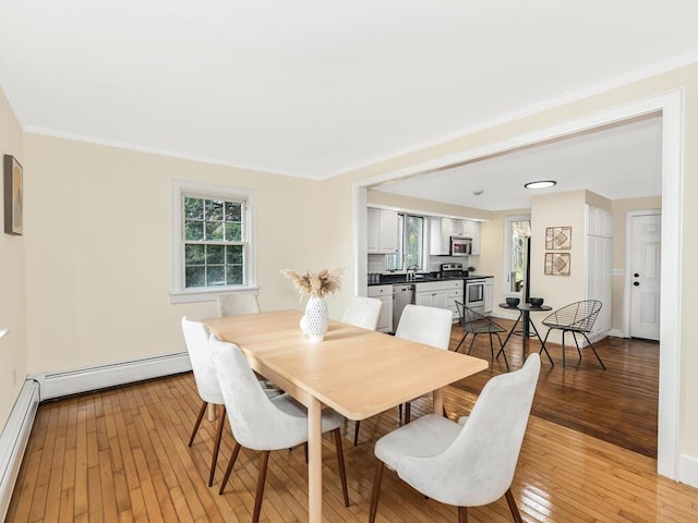 dining area featuring light wood finished floors, baseboard heating, a baseboard radiator, and baseboards