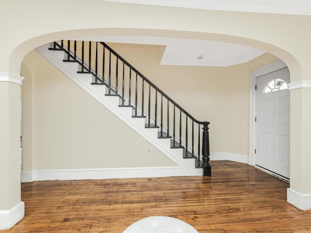 entrance foyer with arched walkways, wood finished floors, and baseboards