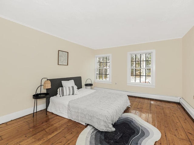 bedroom featuring baseboards, baseboard heating, wood finished floors, and ornamental molding