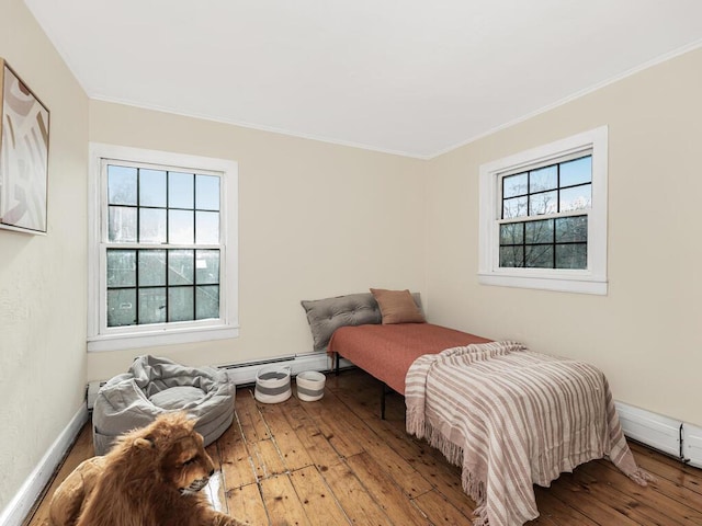 bedroom featuring baseboards, baseboard heating, crown molding, and wood finished floors