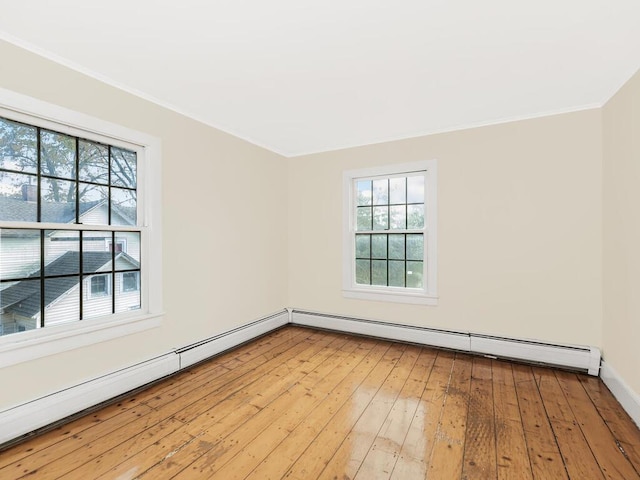 empty room featuring crown molding, baseboard heating, a baseboard heating unit, light wood-type flooring, and baseboards