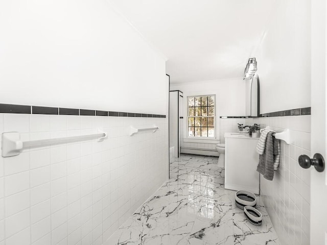 bathroom featuring marble finish floor, wainscoting, toilet, and tile walls