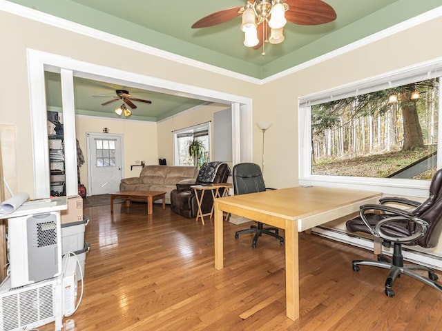 home office with heating unit, crown molding, a ceiling fan, and wood finished floors