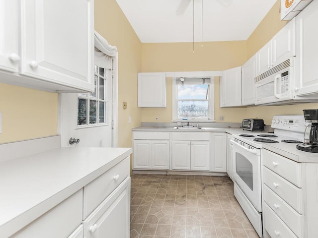 kitchen featuring light tile patterned floors, light countertops, white cabinetry, a sink, and white appliances