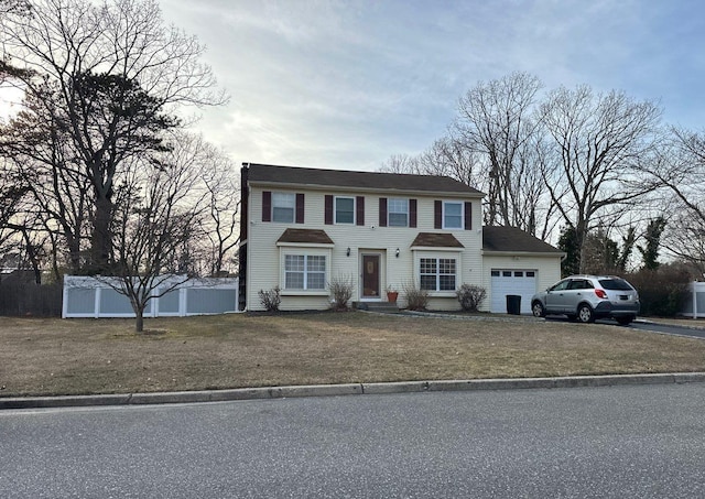 colonial-style house featuring a front lawn and an attached garage