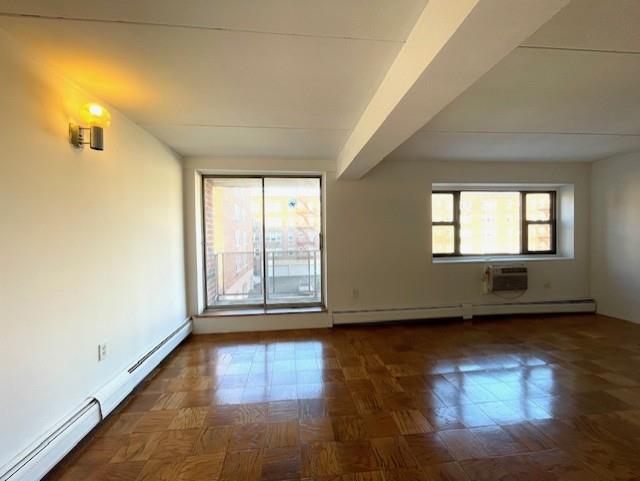 empty room with a baseboard heating unit, a wall unit AC, and beam ceiling