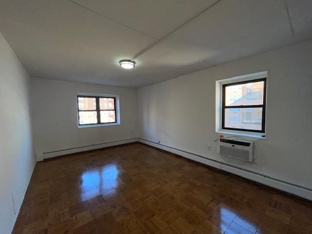 unfurnished room with a wall mounted AC and a baseboard radiator