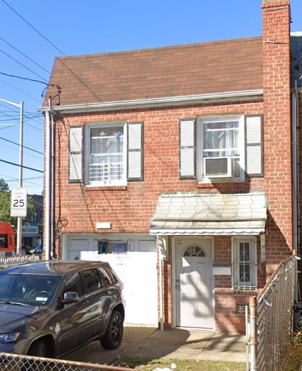 view of front of home with a garage, brick siding, fence, and a chimney