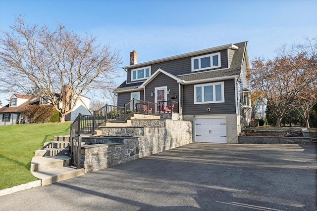 view of front of property featuring a front yard, driveway, an attached garage, a chimney, and stairs