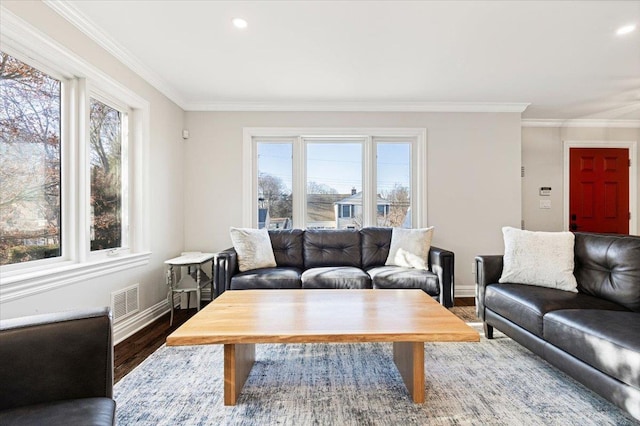 living area featuring a wealth of natural light, visible vents, wood finished floors, and ornamental molding