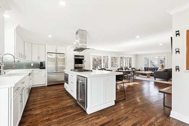 kitchen with beverage cooler, island exhaust hood, a sink, stainless steel appliances, and light countertops