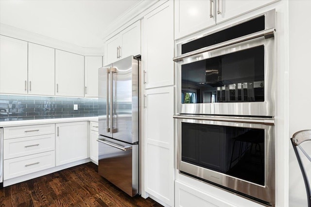 kitchen with dark wood finished floors, white cabinetry, stainless steel appliances, light countertops, and decorative backsplash