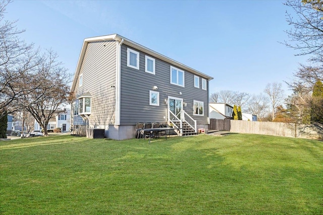 rear view of house with central AC unit, entry steps, a yard, and fence