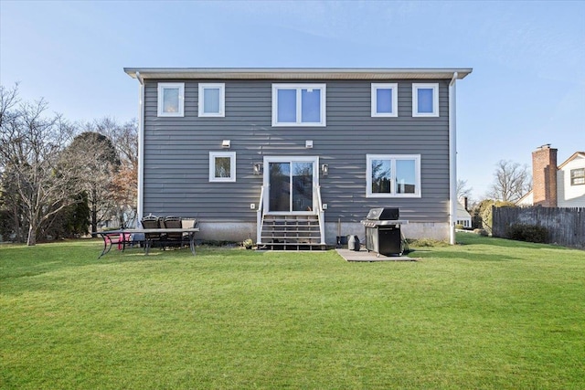 back of house featuring entry steps, a yard, and fence