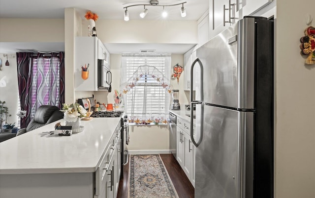 kitchen with stainless steel appliances, white cabinets, and dark wood-style floors