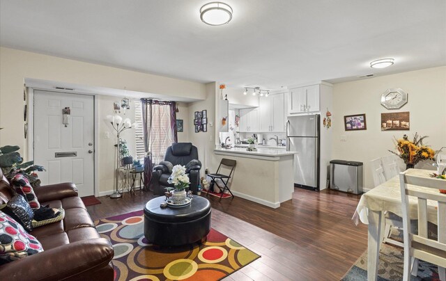 living area with dark wood-style floors, visible vents, and baseboards