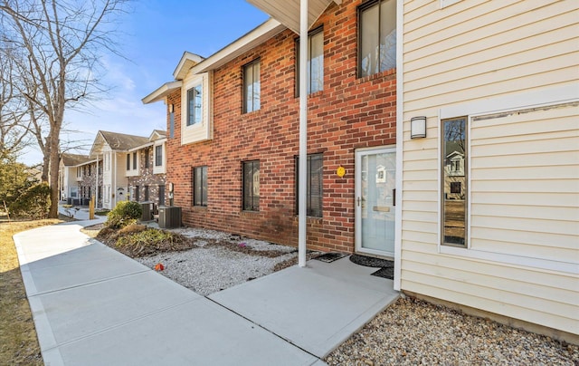 entrance to property featuring central AC and brick siding