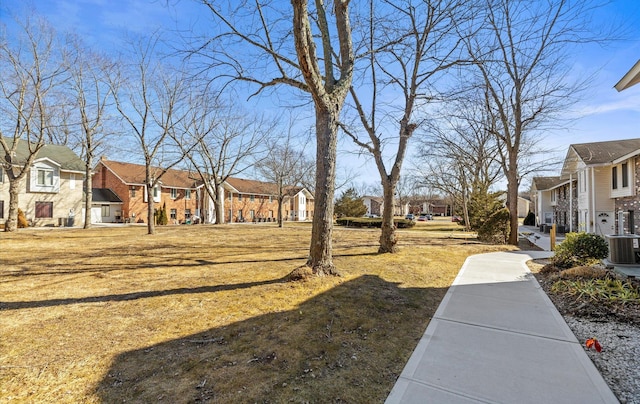 view of yard featuring a residential view and central AC unit