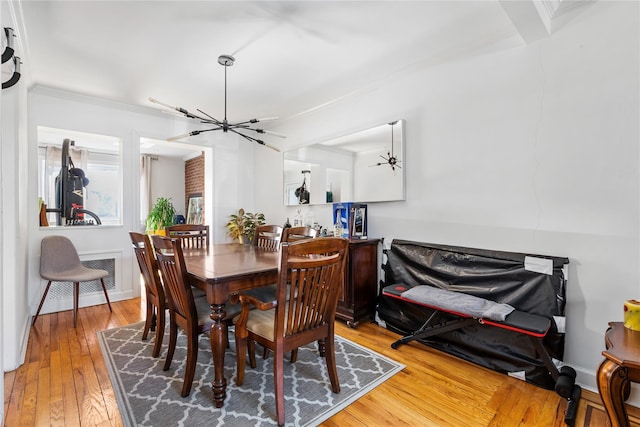 dining space with a notable chandelier, wood finished floors, visible vents, baseboards, and ornamental molding