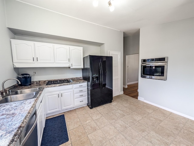 kitchen with baseboards, white cabinetry, stainless steel appliances, and a sink